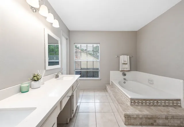a spacious bathroom with a tub sink and mirror