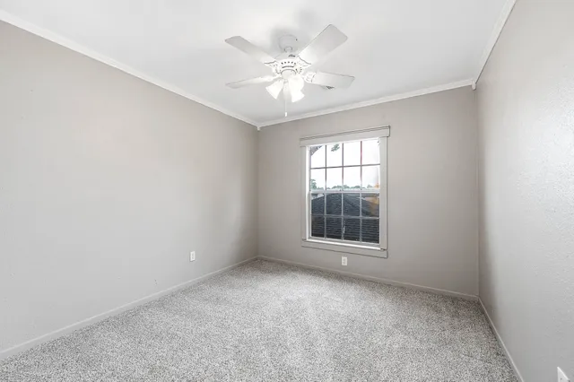an empty room with windows and chandelier fan