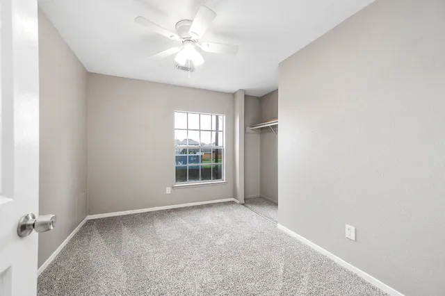 an empty room with windows and fan