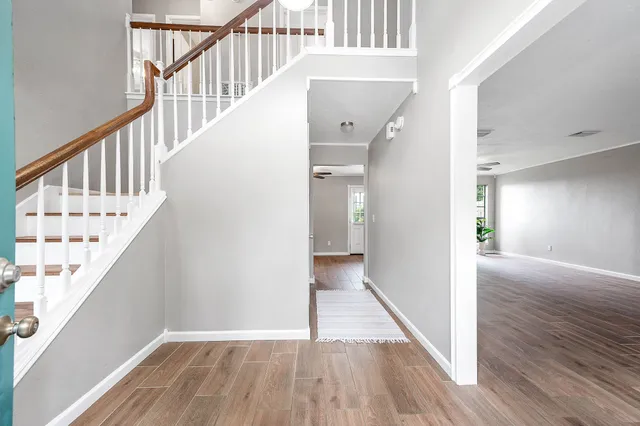 a view of a hallway with wooden floor and staircase