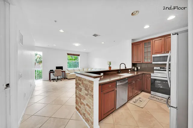 a kitchen with stainless steel appliances granite countertop a sink a stove and a refrigerator