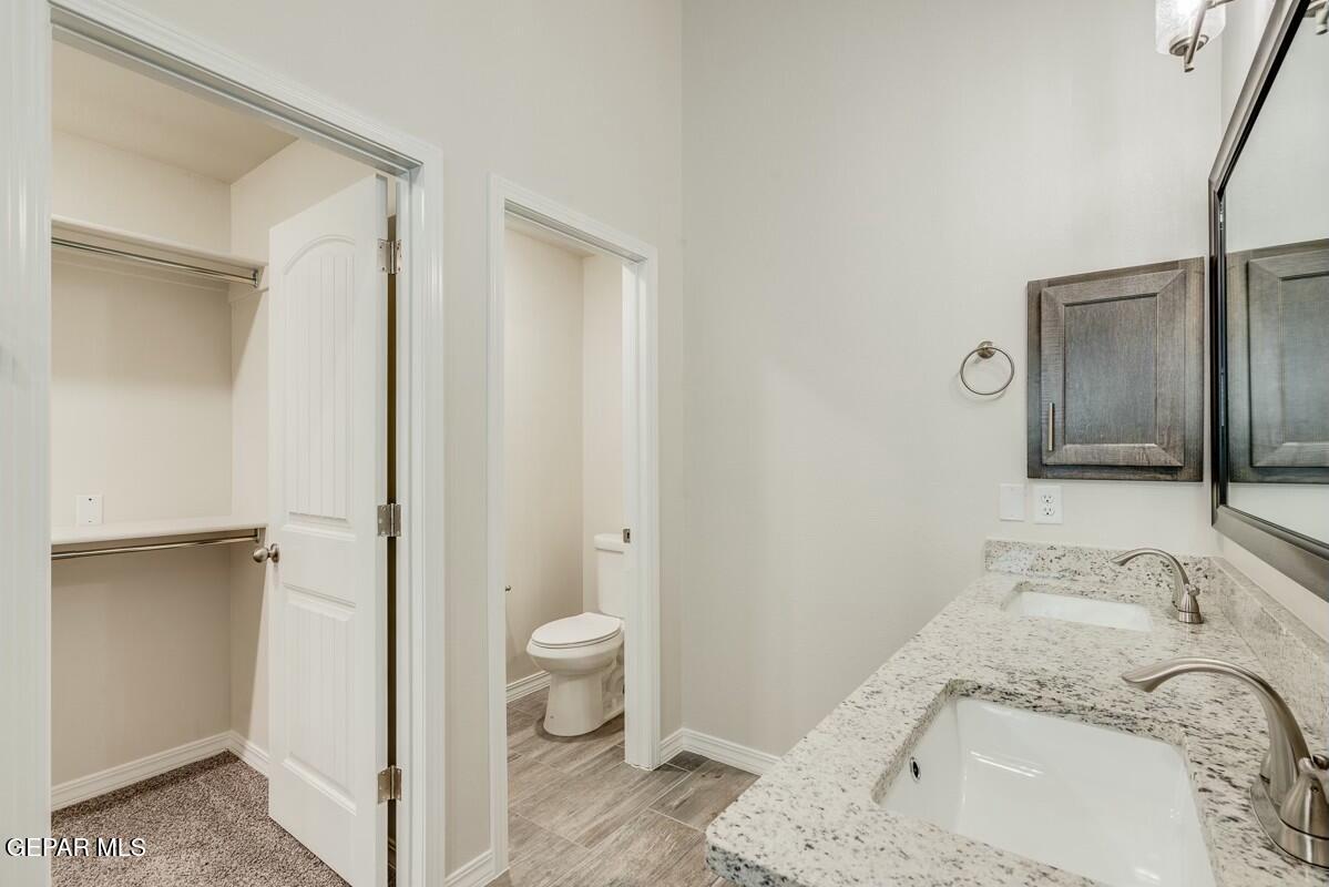 6064 Fall Ridge Street Sunland Park, NM 88008 - Photo 22 of 26 a bathroom with a granite countertop sink toilet and shower