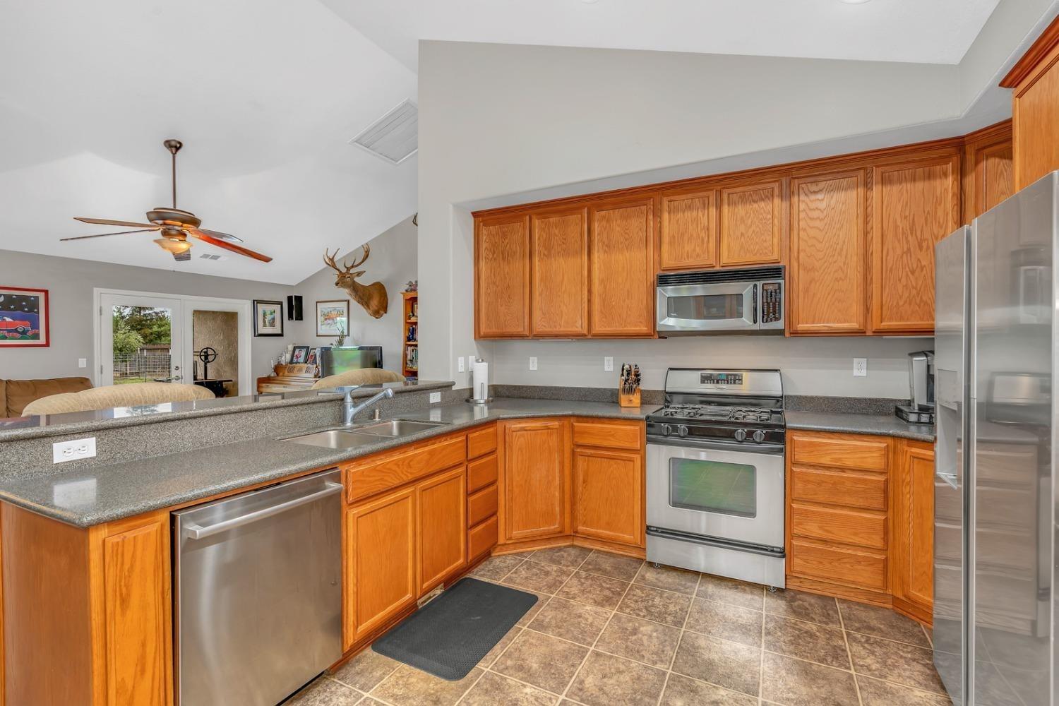 14155 Buchanan Hollow Road Le Grand, CA 95333 - Photo 29 of 46 a kitchen with stainless steel appliances granite countertop a sink a stove a refrigerator cabinets and a window