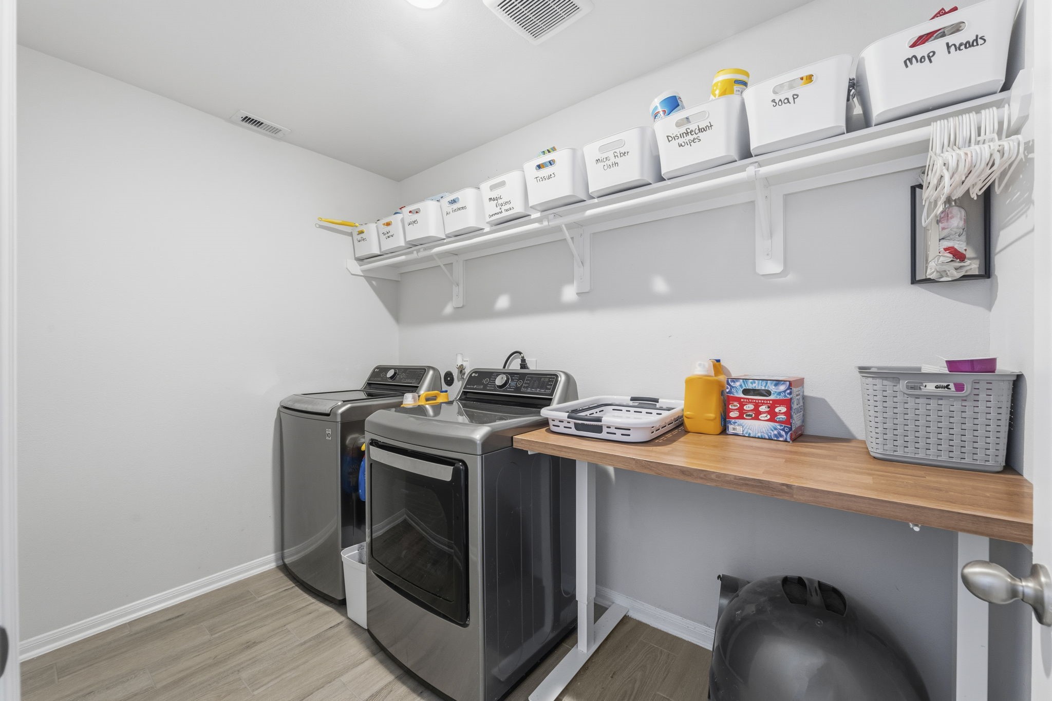 2401 Abbot Brk Drive Rosharon, TX 77583 - Photo 23 of 50 This spacious laundry room combines practicality with versatility, featuring durable wood-look tile flooring, convenient open shelving, and ample flex space for a secondary refrigerator, household planning desk, or a functional mudroom-style bench area for backpacks and shoes. Thoughtfully designed to support busy daily living, this space adds both comfort and convenience to the home.