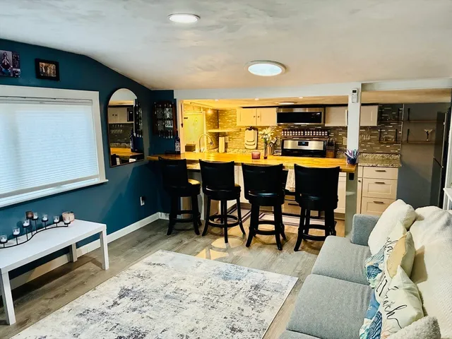 a living room with stainless steel appliances kitchen island granite countertop furniture wooden floor and a window