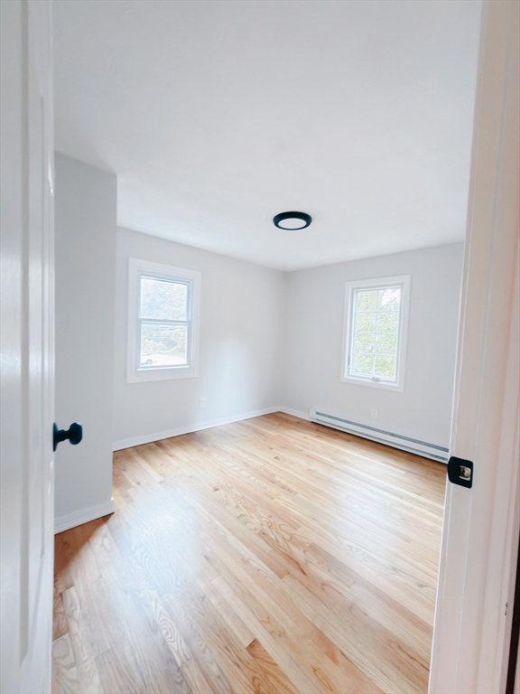 206 Treetop Avenue Springfield, MA 01118 - Photo 9 of 16 an empty room with wooden floor and windows