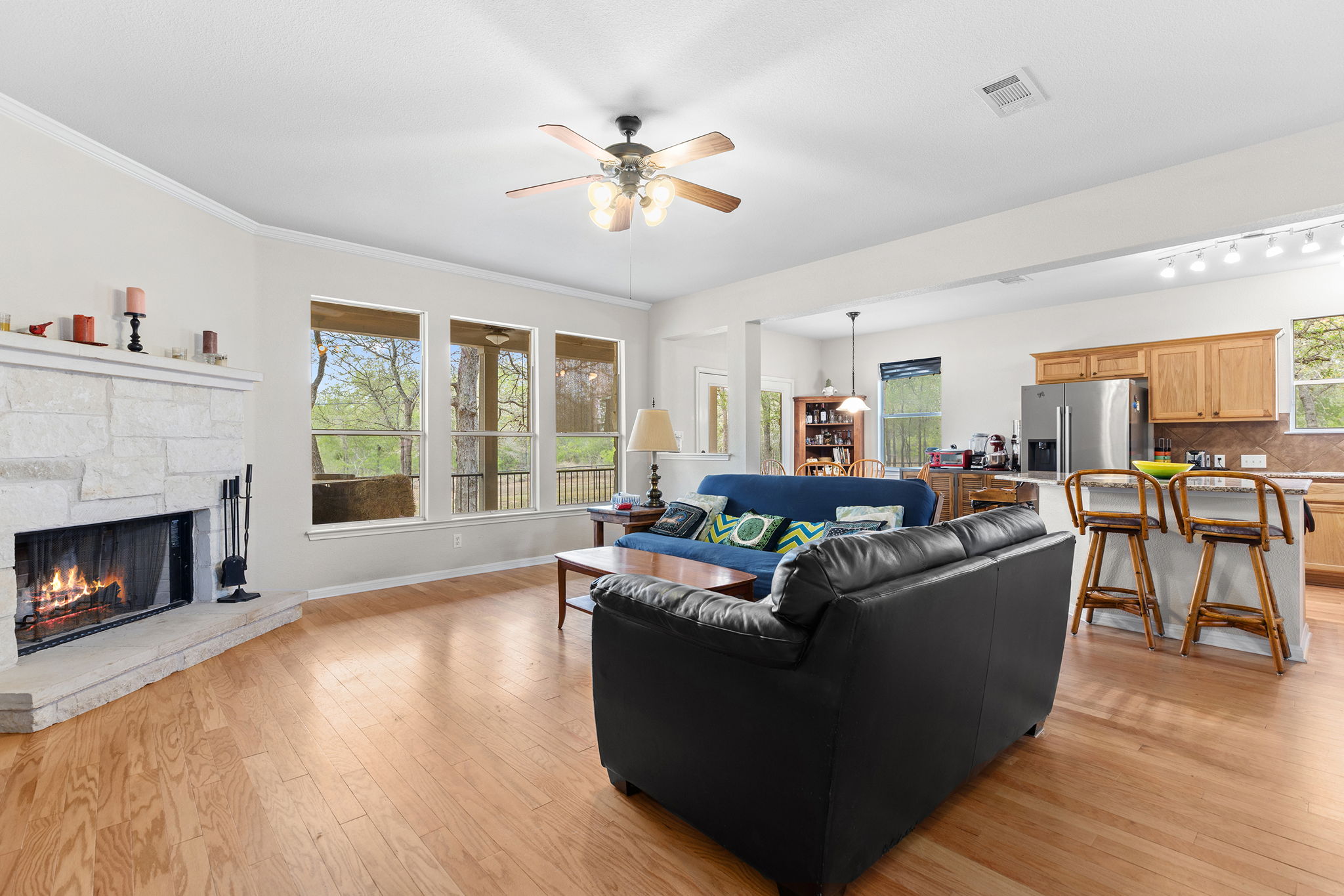 202 The Oaks Boulevard Elgin, TX 78621 - Photo 14 of 40 Living area featuring light wood finished floors, a stone fireplace, ceiling fan, and healthy amount of natural light