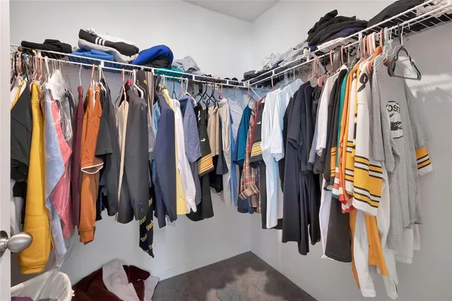 a view of walk in closet with clothes and shoes
