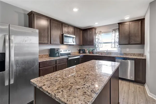 a kitchen with stainless steel appliances granite countertop a sink refrigerator and microwave