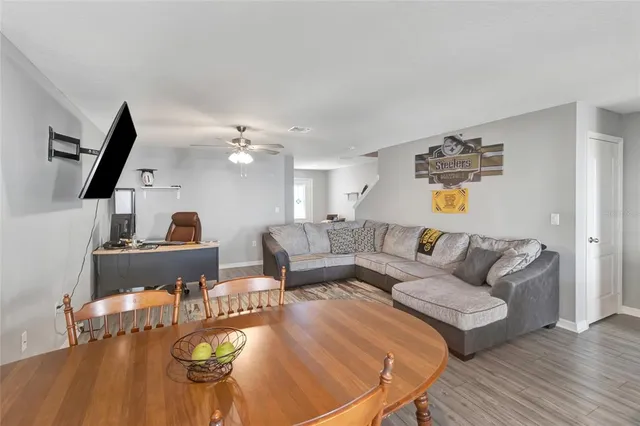 a living room with couches and kitchen view with wooden floor