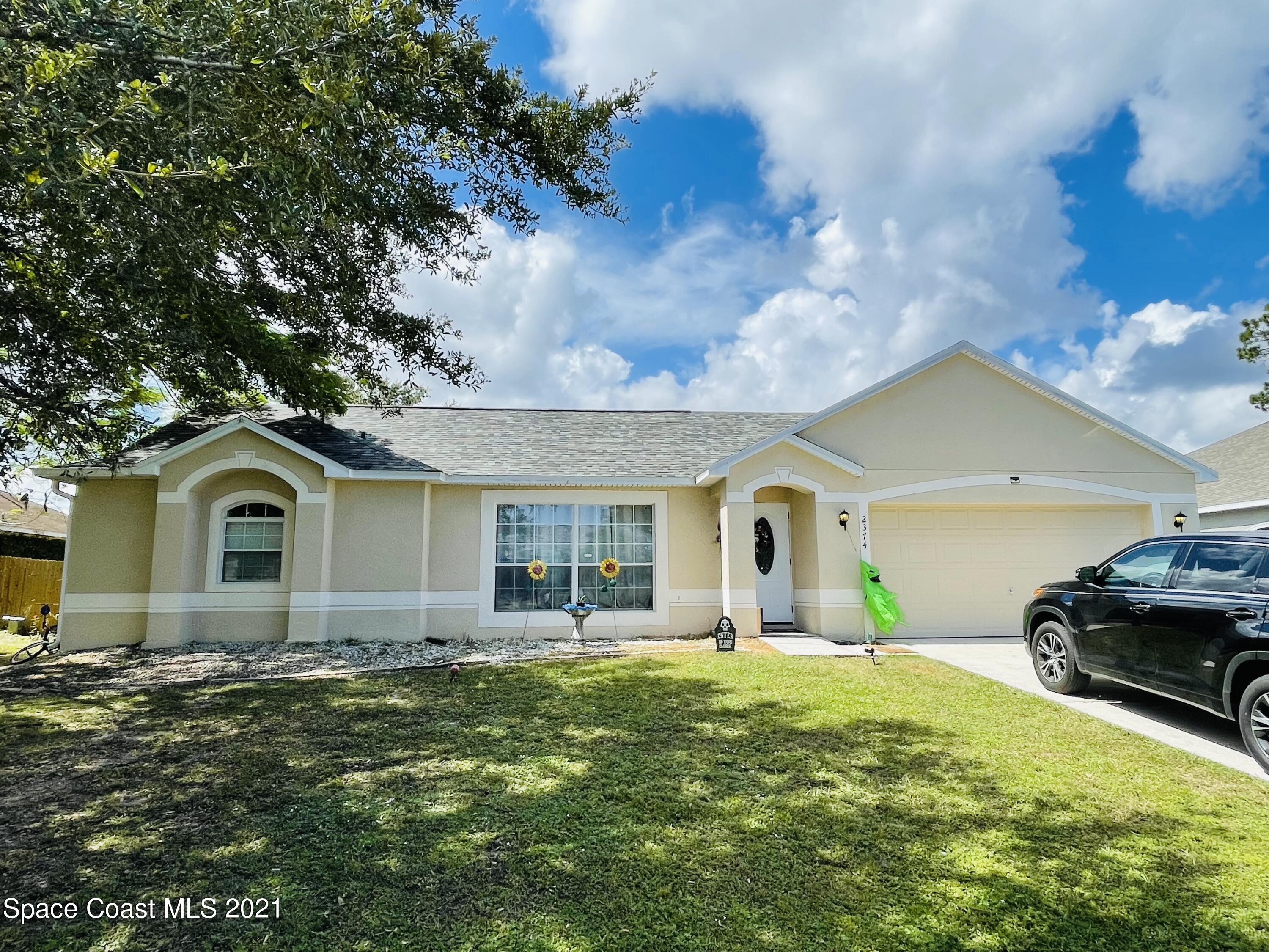 2374 Angel Road Palm Bay, FL 32909 - Photo 1 of 19 a front view of a house with a yard and garage