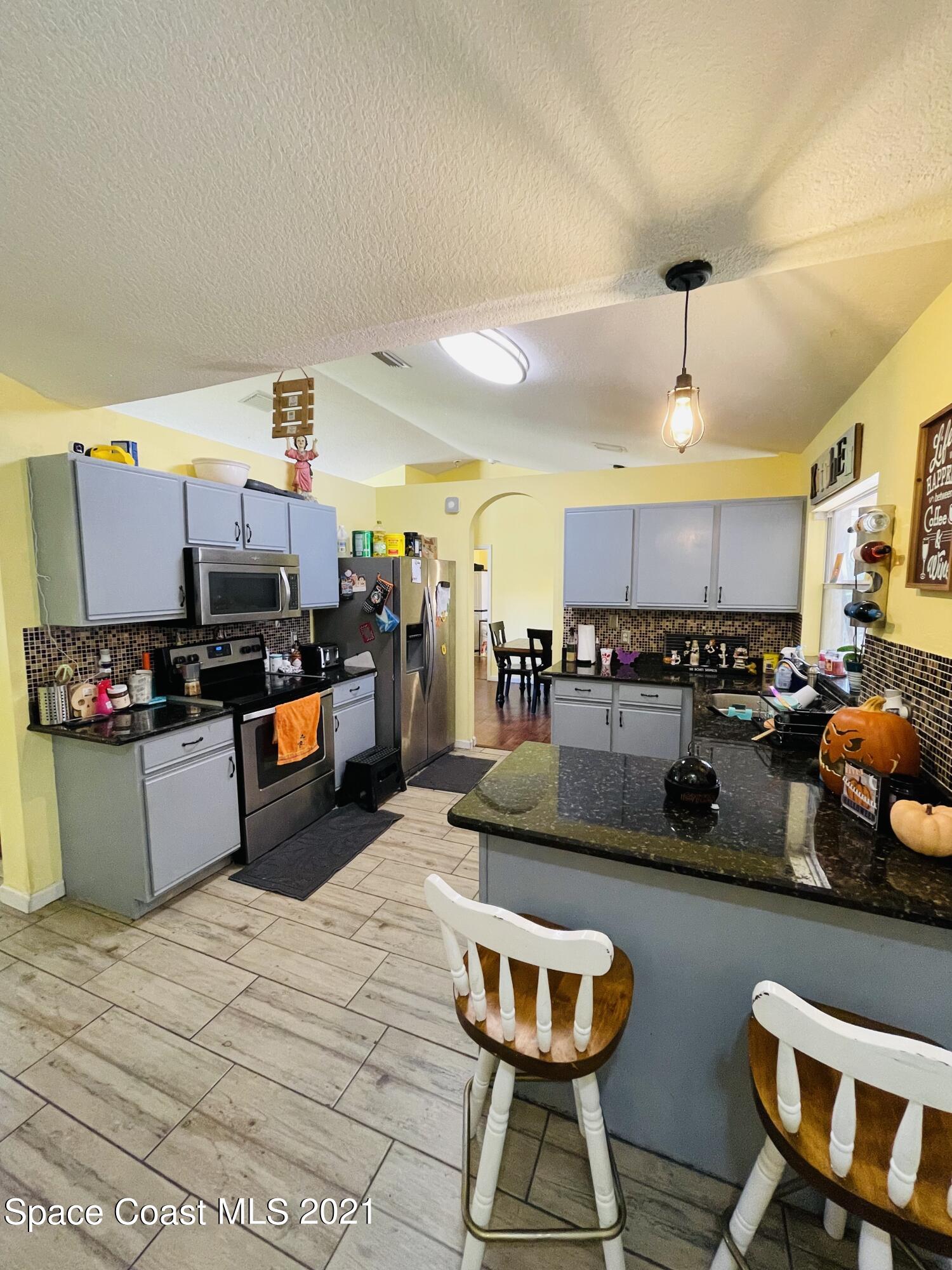 2374 Angel Road Palm Bay, FL 32909 - Photo 5 of 19 a kitchen with stainless steel appliances granite countertop a sink stove and refrigerator