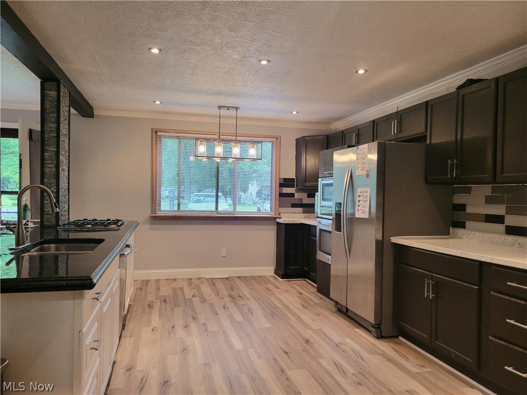 4895 Lear Nagle Road North Ridgeville, OH 44039 - Photo 4 of 27 Kitchen featuring tasteful backsplash, light wood-type flooring, a notable chandelier, a textured ceiling, and sink