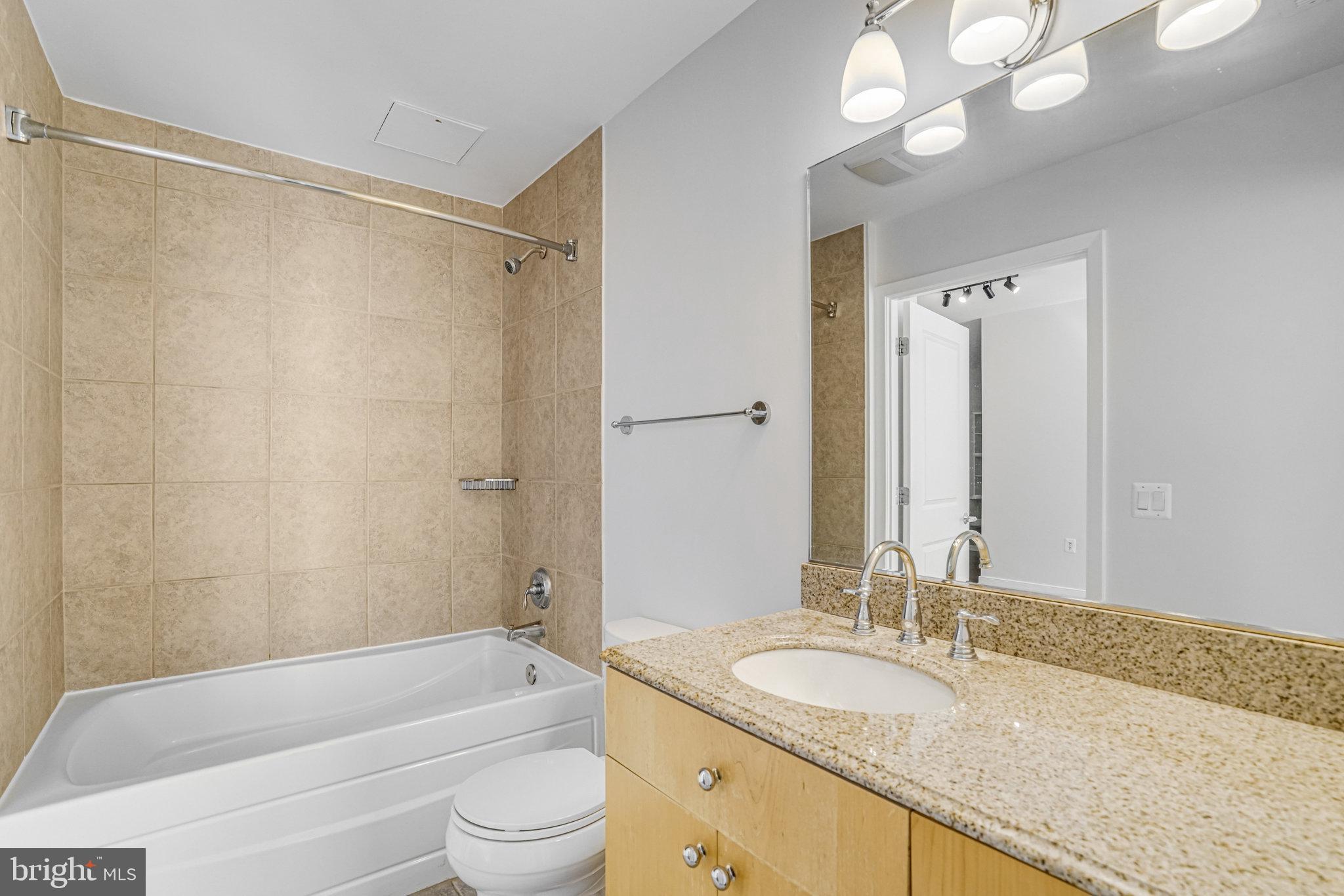 820 North Pollard Street, Unit 915 Arlington, VA 22203 - Photo 21 of 30 a bathroom with a granite countertop sink a toilet and shower