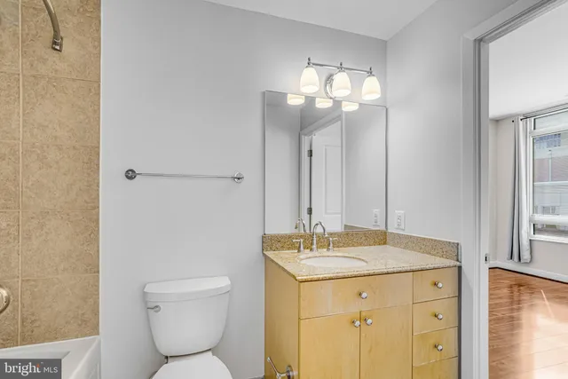 a bathroom with a granite countertop sink a toilet and shower