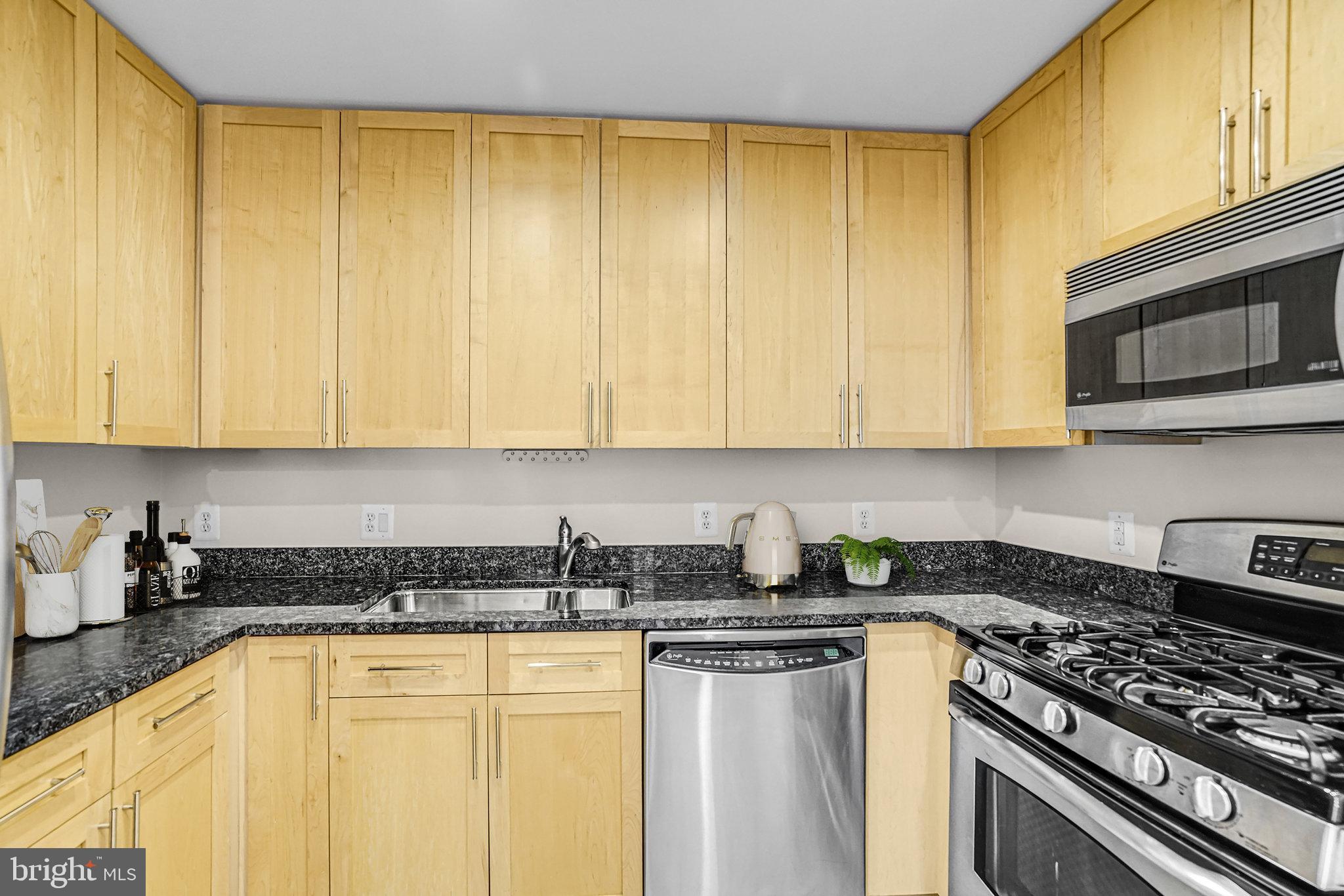 820 North Pollard Street, Unit 915 Arlington, VA 22203 - Photo 4 of 30 a kitchen with stainless steel appliances granite countertop a stove a sink and dishwasher a refrigerator with wooden cabinets