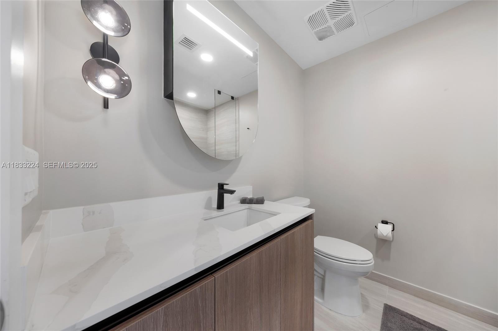 580 72nd Street, Unit 910 Miami Beach, FL 33141 - Photo 59 of 60 a bathroom with a sink a toilet and a mirror