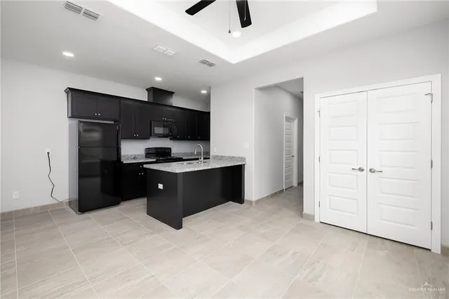 a kitchen with stainless steel appliances kitchen island granite countertop a refrigerator and a stove top oven