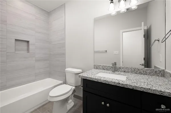 a bathroom with a granite countertop sink a toilet a mirror and bathtub