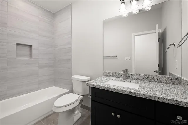 a bathroom with a granite countertop sink a toilet a mirror and bathtub