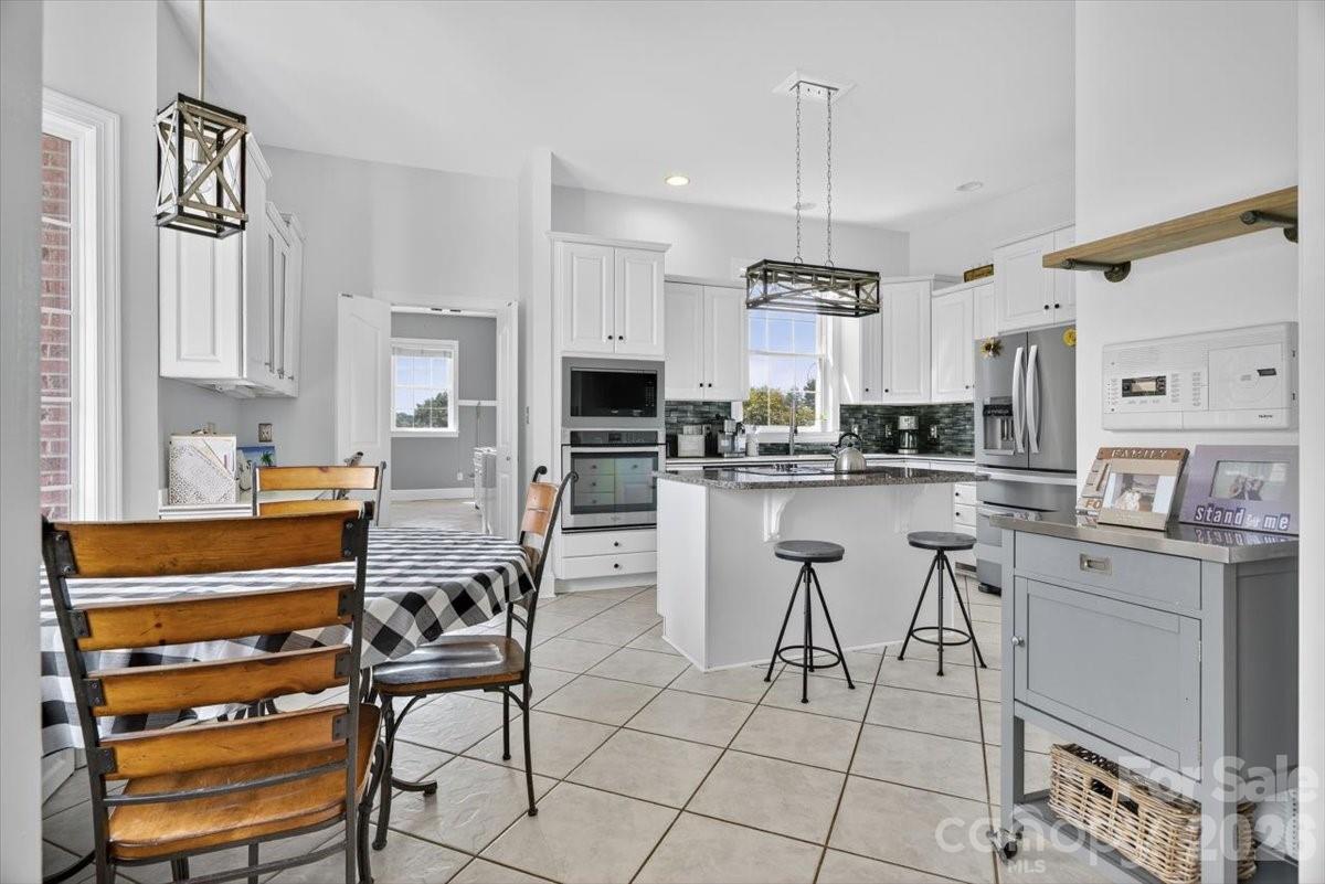 498 Johnson Dairy Road Mooresville, NC 28115 - Photo 16 of 43 a kitchen with stainless steel appliances a dining table chairs sink and cabinets