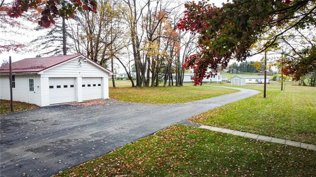 a view of a white house with a large tree and wooden fence