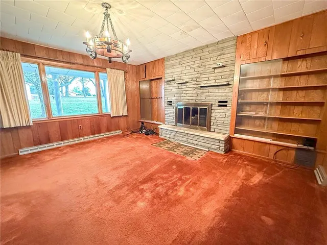 en empty room with a fireplace and chandelier