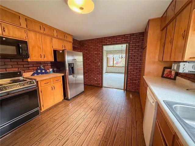a kitchen with a sink wooden floor and stainless steel appliances