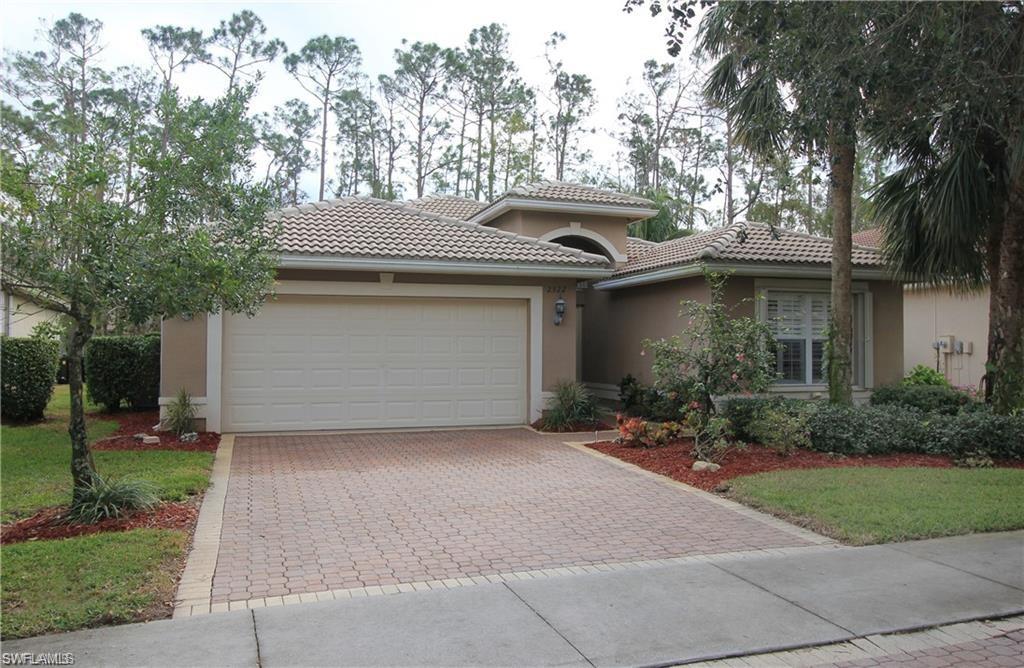 2322 Butterfly Palm Drive Naples, FL 34119 - Photo 1 of 32 a front view of a house with a garden and plants