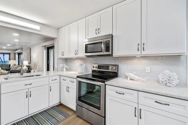 a kitchen with granite countertop white cabinets white stainless steel appliances and a sink