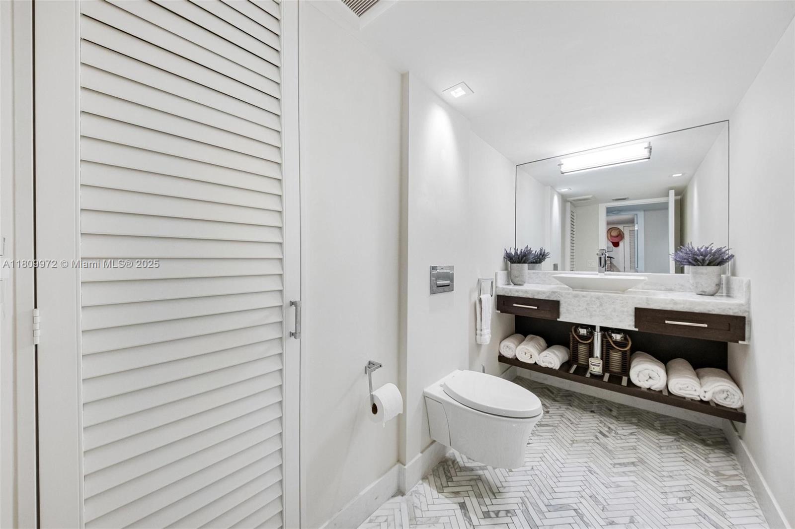 2901 South Bayshore Drive, Unit 17G/H Miami, FL 33133 - Photo 57 of 81 a bathroom with a toilet a sink and mirror