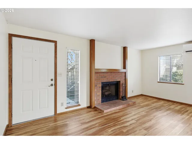 an empty room with wooden floor fireplace and windows