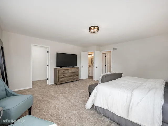 a spacious bedroom with a bed and a flat screen tv