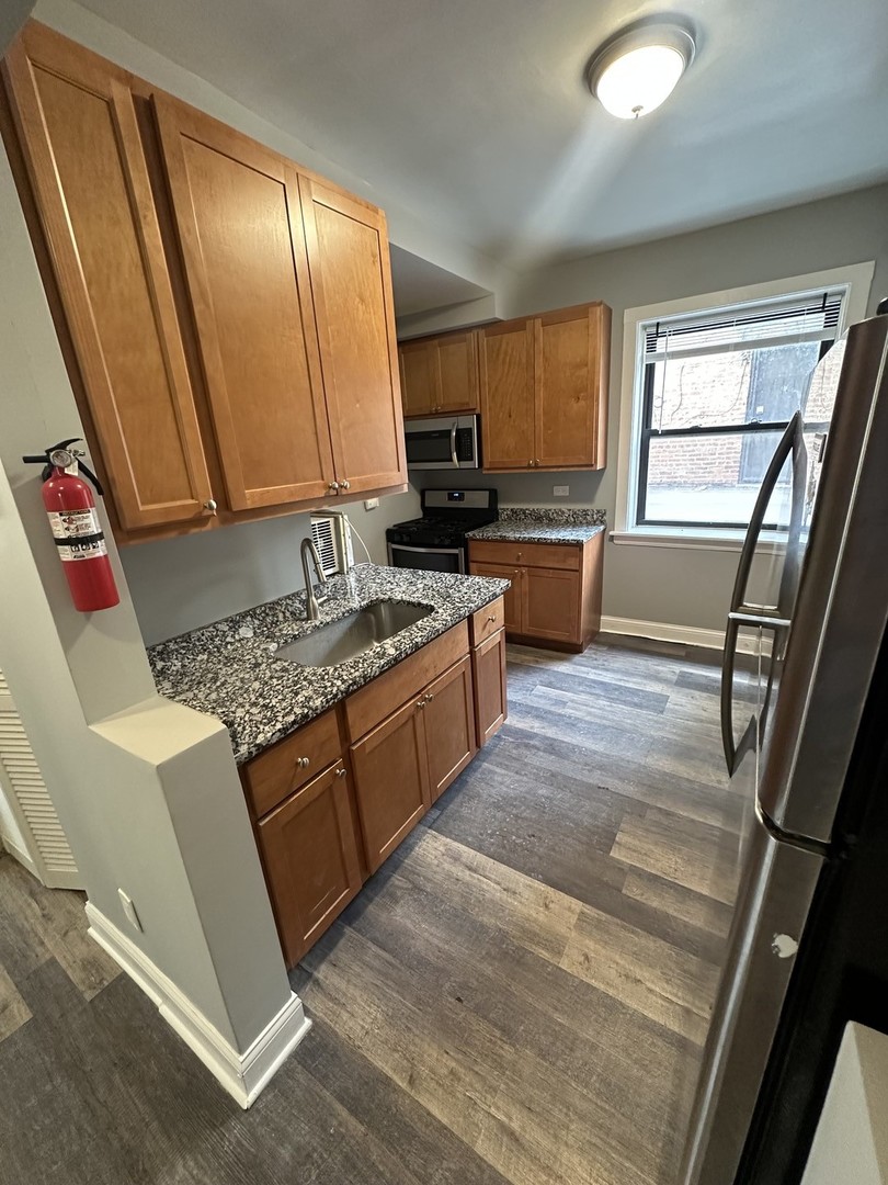 1614 North Harding Avenue, Unit G Chicago, IL 60647 - Photo 4 of 16 a kitchen with granite countertop a stove a sink and a refrigerator