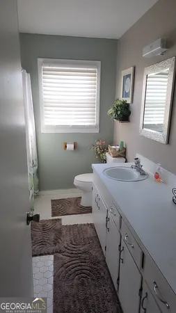 a bathroom with a granite countertop sink a toilet a mirror and window