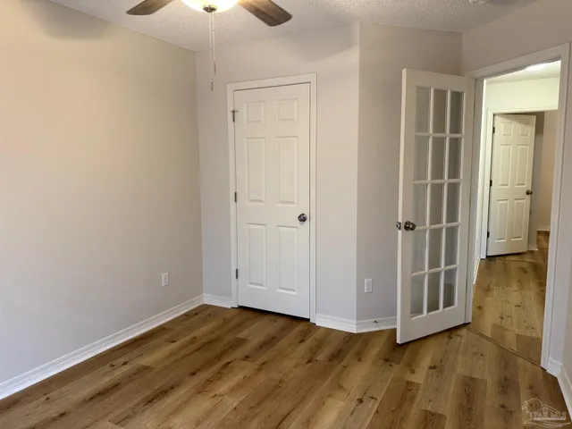 an empty room with wooden floor cabinet and windows