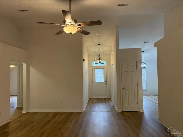 an empty room with wooden floor and ceiling fan