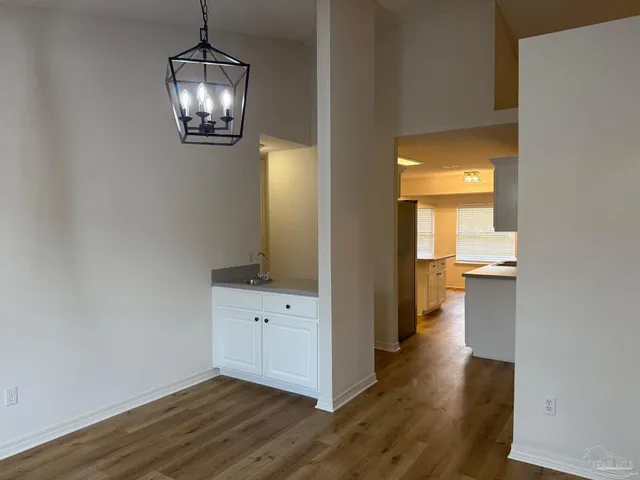 an empty room with wooden floor mirror and windows