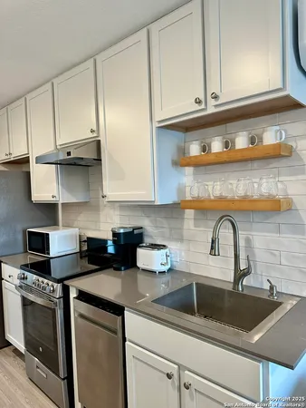 a kitchen with stainless steel appliances granite countertop a sink a stove and cabinets