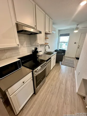 a kitchen with granite countertop a sink a stove and wooden floor