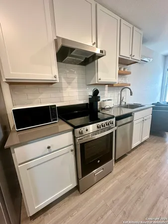 a kitchen with stainless steel appliances white cabinets and a stove top oven
