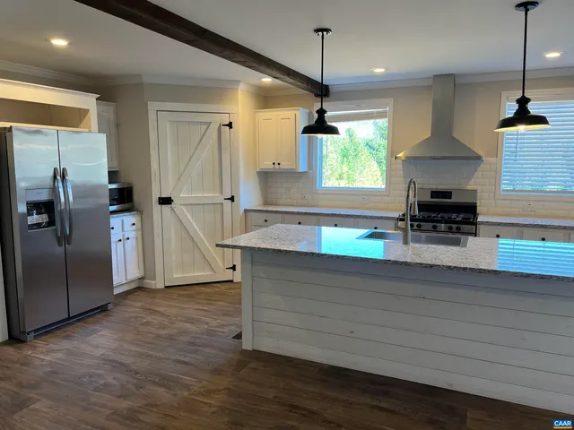 a kitchen with stainless steel appliances granite countertop a refrigerator a sink a stove and a wooden floors