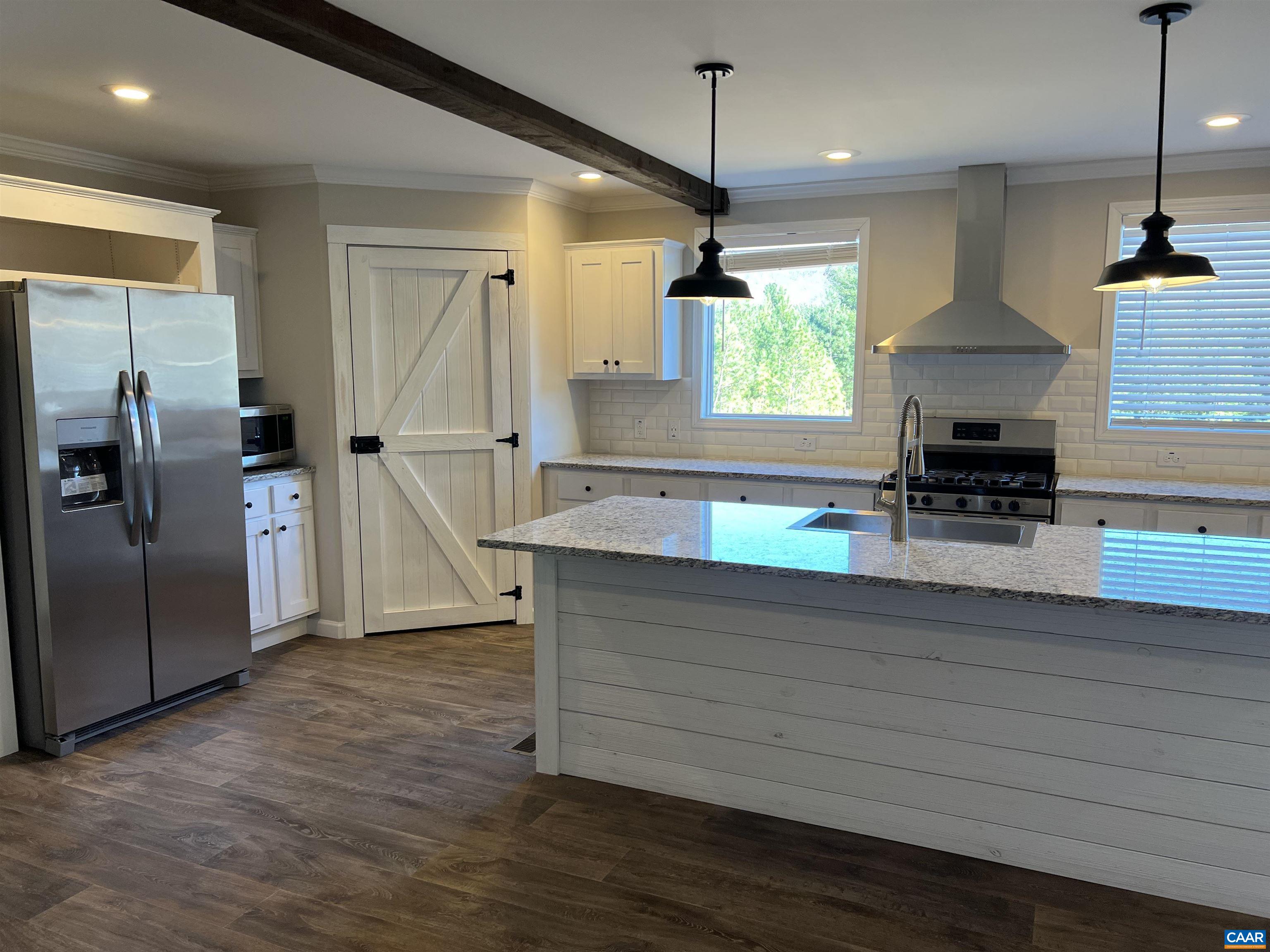 a kitchen with stainless steel appliances granite countertop a refrigerator a sink a stove and a wooden floors