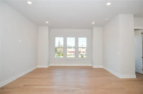 a view of an empty room with a window and a kitchen