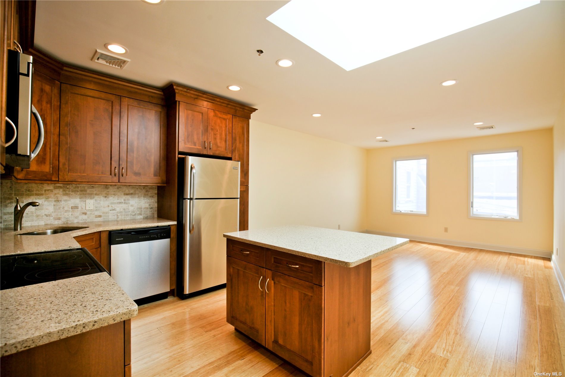 a kitchen with stainless steel appliances granite countertop a sink a stove a refrigerator cabinets and wooden floor