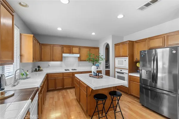 a kitchen with stainless steel appliances granite countertop sink stove refrigerator and wooden cabinets