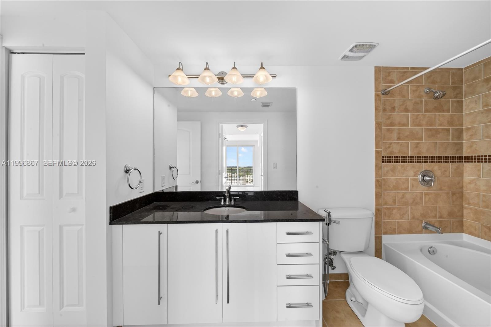 7350 Southwest 89th Street, Unit 1703S Miami, FL 33156 - Photo 16 of 29 a bathroom with a granite countertop sink vanity mirror bathtub shower