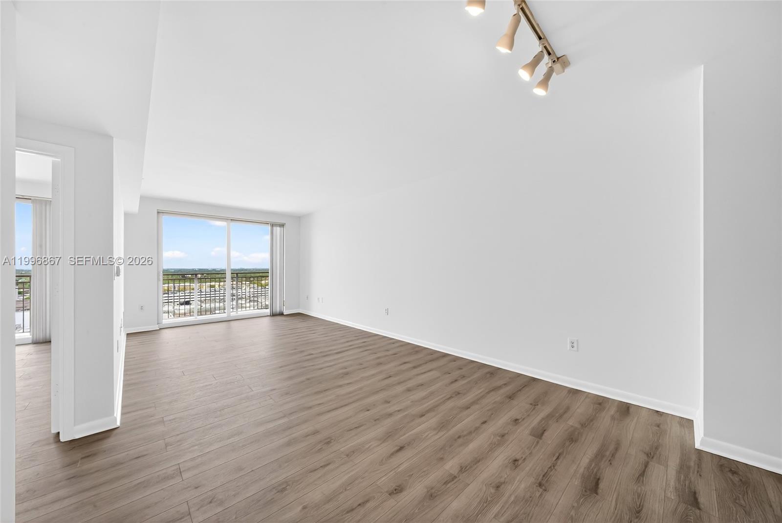 7350 Southwest 89th Street, Unit 1703S Miami, FL 33156 - Photo 9 of 29 a view of an empty room with wooden floor and a window
