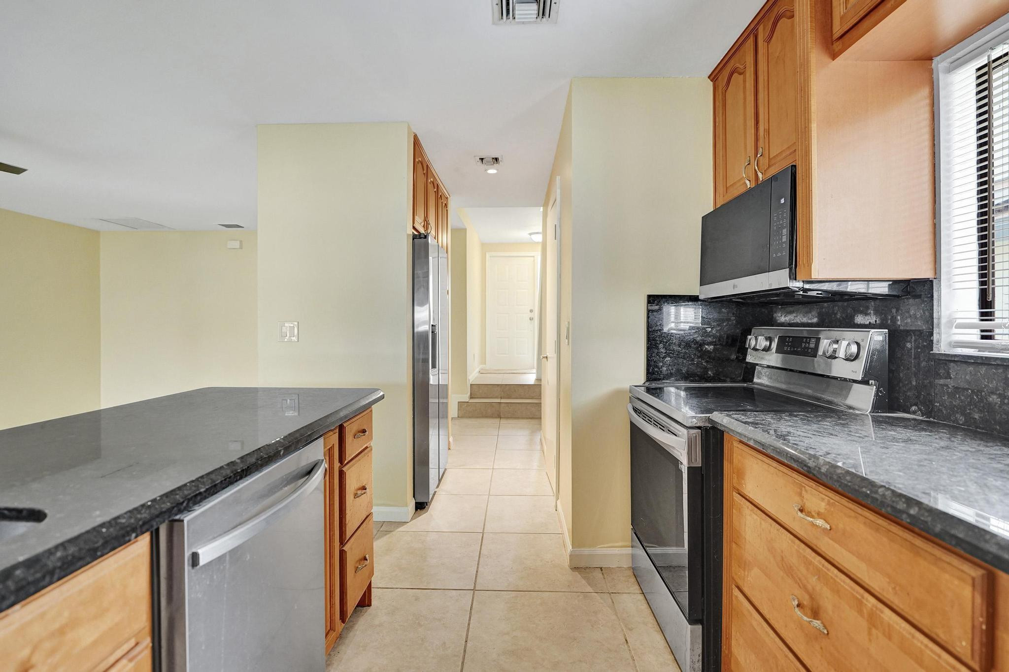 5425 Cleveland Road Delray Beach, FL 33484 - Photo 12 of 39 a kitchen with stainless steel appliances granite countertop a sink stove and refrigerator