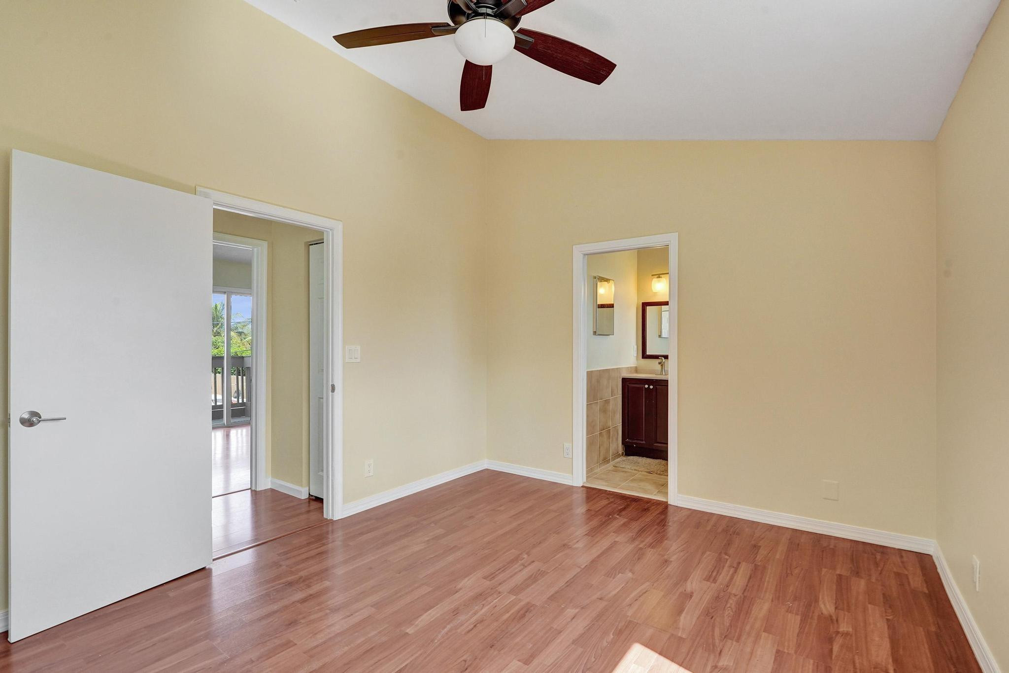 5425 Cleveland Road Delray Beach, FL 33484 - Photo 27 of 39 an empty room with wooden floor chandelier fan and kitchen view